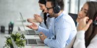 three contact center agents headsets laptops