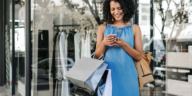 Woman holding shopping bags and phone 1100 x 550 px