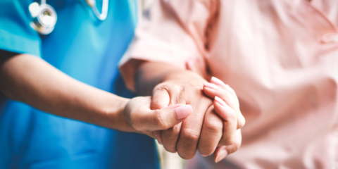 Close up of an older patient being supported by the hand of a doctor.