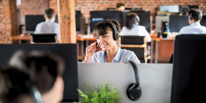 Smiling woman agent talks to a customer over her headset in the contact center.