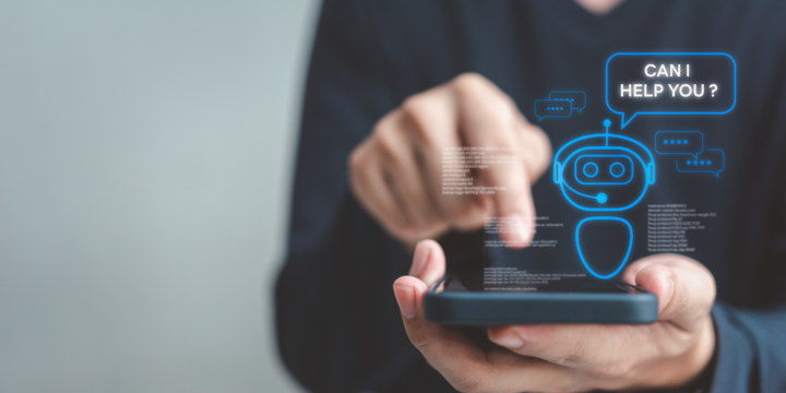 A close-up image of a person pressing a button on a cell phone. There is a graphic pop-up hovering over the phone of a robot with the words "Can I help you?" next to it.