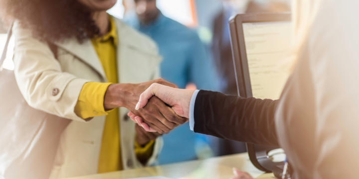 Close-up of the hands of a female customer as they shake hand with an employee over a counter.