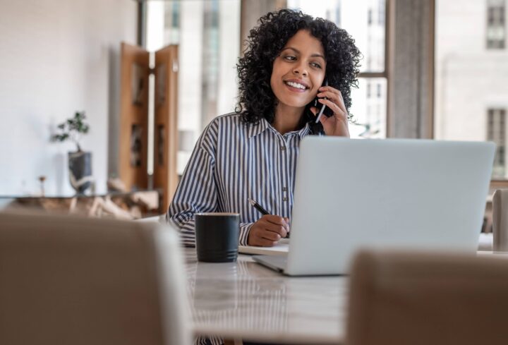 woman on phone looking at laptop computer