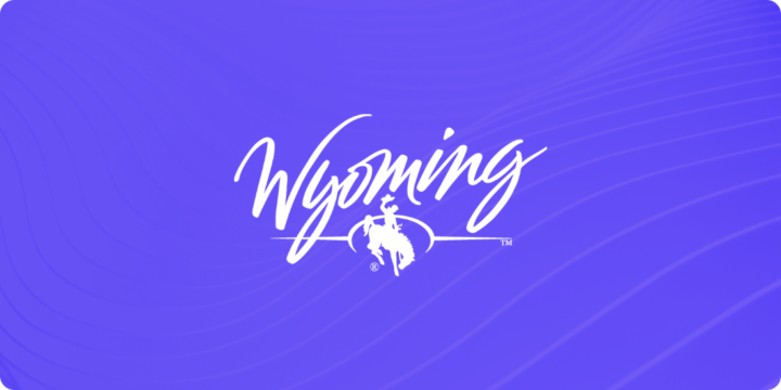 The state of Wyoming logo, including a cowboy riding a bucking bronco, on a purple background.